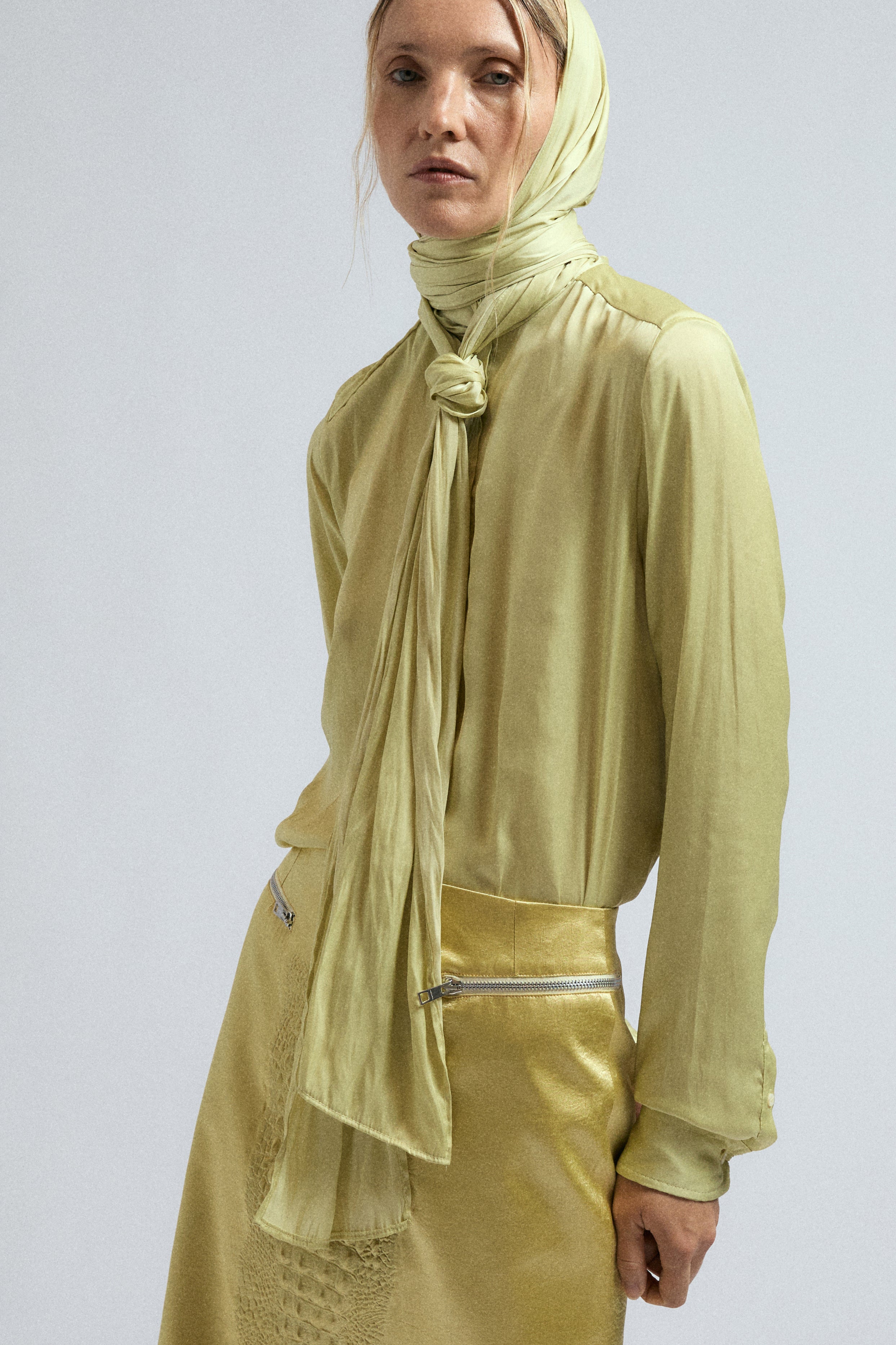 Woman wears JordanLuca's Satin Canary Yellow bow shirt, paired with the Canary Bumpster skirt