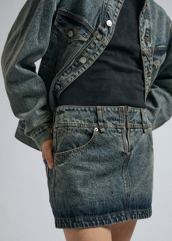 Detailed shot of woman wearing JordanLuca's FW24 marble mini fuse skirt, with discreet metal zip.