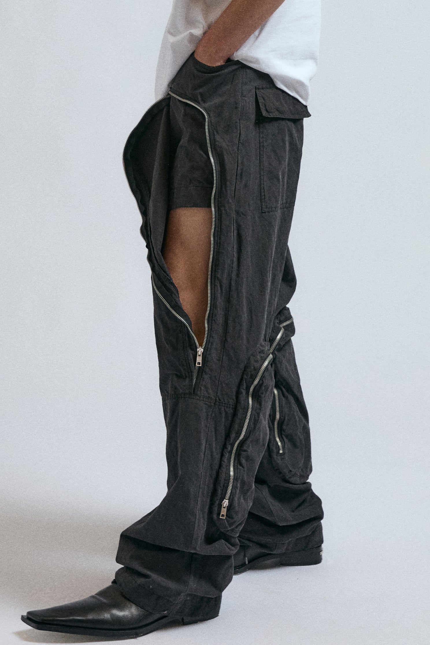 Man wearing black JordanLuca Voltage Cargo trousers, with the zip partially open.